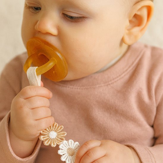 attache tetine bebe qui tient sa tetine dans sa main