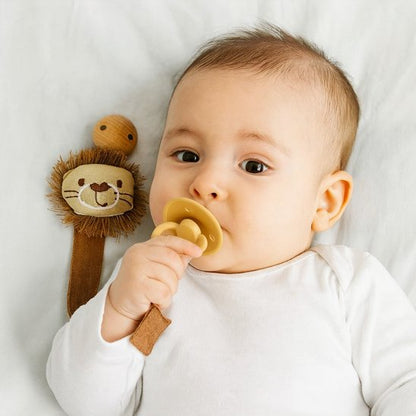attache tetine bebe qui tient sa tetine dans sa bouche